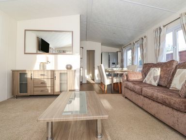 A living room with sofa coffee table sideboard dining table and chairs at Pegasus in Felmoor Park
