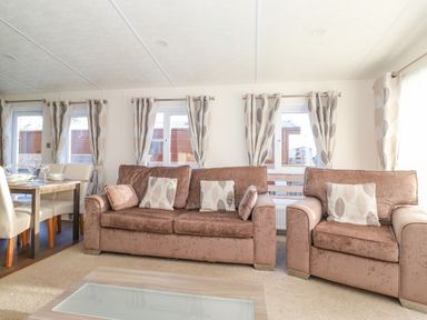 A living room with two brown sofas and a dining table with chairs at Pegasus in Felmoor Park