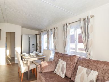 A dining area with table set for four chairs and a sofa with patterned cushions at Pegasus in Felmoor Park
