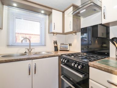 A kitchen with a double sink a gas stove a toaster and knives on the counter at Pegasus in Felmoor Park