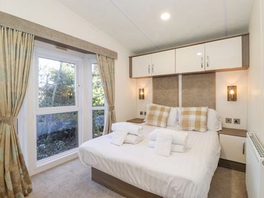 A bedroom with bed pillows and towels near a window with curtains at Pegasus Felmoor Park