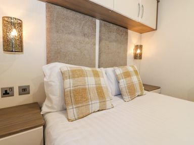 A bedroom with a double bed two plaid pillows wall lamps and nightstands at Pegasus Felmoor Park