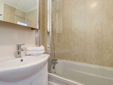 A bathroom with a sink holding folded towels and a bathtub with a shower at Pegasus in Felmoor Park