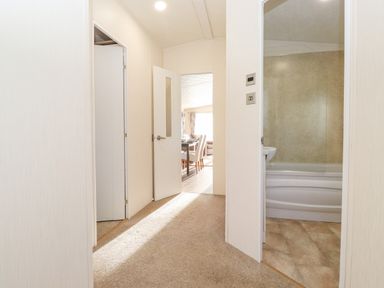 A hallway with doors leading to a bathroom and a dining area at Pegasus in Felmoor Park