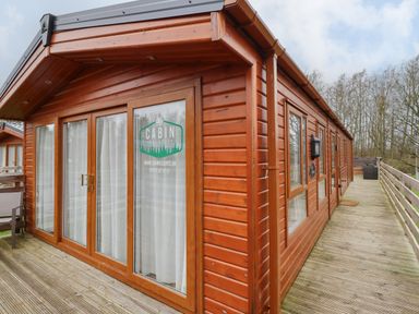 A wooden cabin with glass doors and deck outside at Pegasus in Felmoor Park