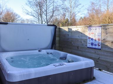 An outdoor hot tub with water and a raised cover surrounded by wooden fencing at Hercules in Felmoor Park