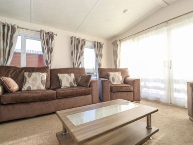 A living room with brown sofas and a wooden coffee table with glass insert at Hercules in Felmoor Park
