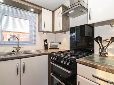 A kitchen with a gas stove a toaster knives utensils and two sinks at Hercules in Felmoor Park