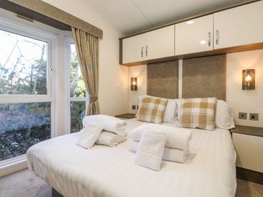 A bedroom with a double bed with towels on it beside a window at Hercules in Felmoor Park