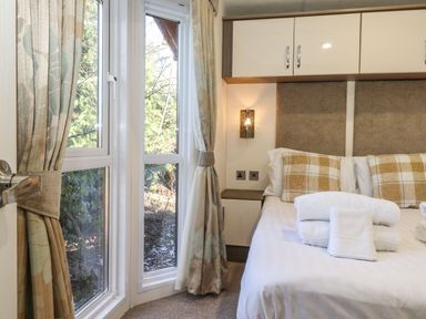 A bedroom with a bed with pillows and folded towels next to windows with curtains at Hercules in Felmoor Park