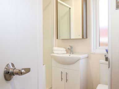 A bathroom with a white sink cabinet towels mirror window and toilet at Hercules in Felmoor Park