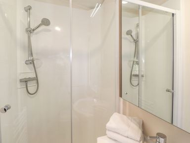 A bathroom with a showerhead mirror and folded towels at Hercules in Felmoor Park