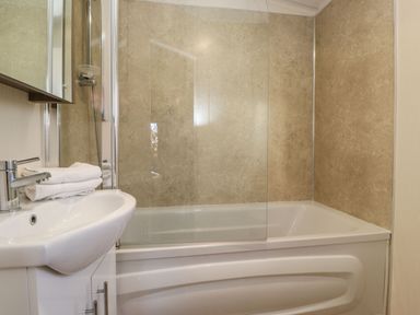A bathroom with a bathtub shower combination and a sink with towels at Hercules in Felmoor Park