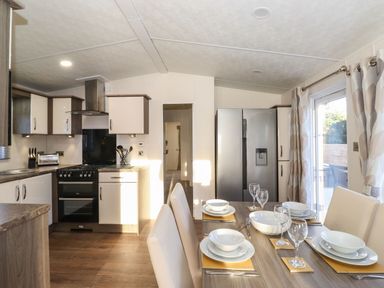 A kitchen and dining area with a stove refrigerator and table set with plates and glasses at Canis Felmoor Park