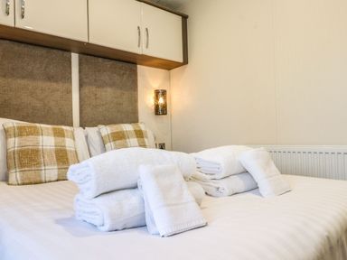 A bedroom with a bed with plaid pillows and neatly folded white towels on the bed at Canis in Felmoor Park