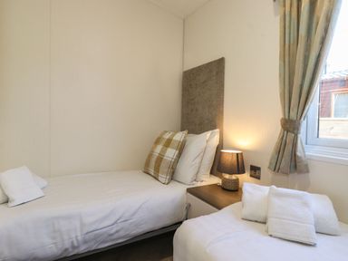 A bedroom with two single beds a nightstand and a window with curtains at Canis Felmoor Park