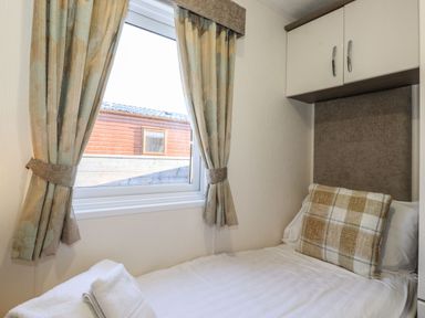 A bedroom with a single bed pillow towels and a window with curtains at Canis Felmoor Park