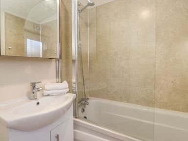 A bathroom with a sink vanity a mirror showerhead and bathtub at Canis in Felmoor Park