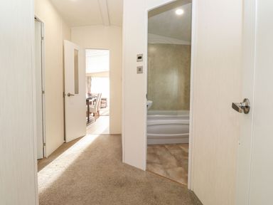 A hallway with carpeted floor and white doors leading to a bathroom and a dining area at Canis in Felmoor Park