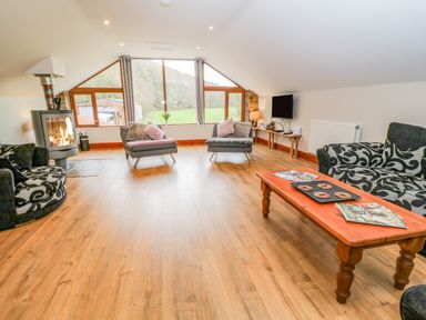 A living room with wood flooring two armchairs patterned sofa coffee table and fireplace at Monkleigh Mill in Monkleigh near Bideford
