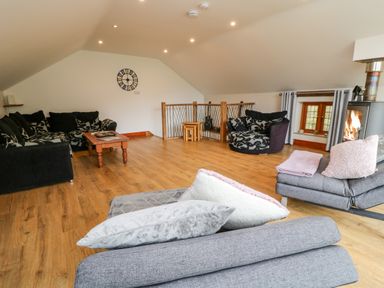 A living room with black and grey sofas a wooden coffee table wooden floor and a fireplace at Monkleigh Mill in Monkleigh near Bideford