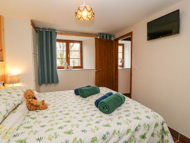 A bedroom with a bed covered in floral bedding and towels on top at Monkleigh Mill in Monkleigh near Bideford