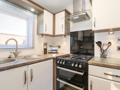 A kitchen with a stove sink utensils toaster and cabinets at Draco in Felmoor Park