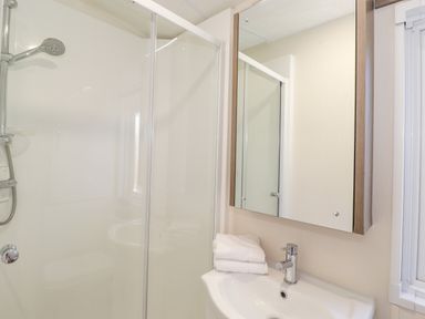 A bathroom with a shower enclosure a sink with faucet and a mirror cabinet with towels at Draco in Felmoor Park