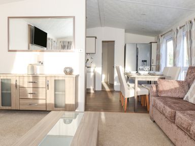 A living room with a sofa table and dining area with a refrigerator at Ursa in Felmoor Park