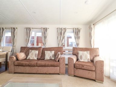 A living room with brown sofas and patterned curtains at Ursa in Felmoor Park