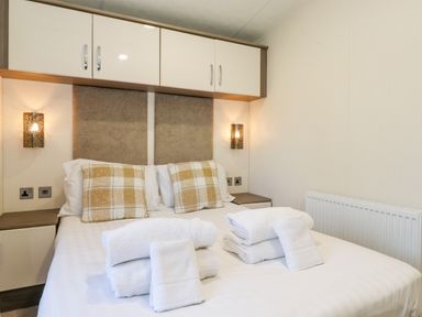 A bedroom with a double bed two plaid pillows and folded white towels on the bed at Ursa in Felmoor Park