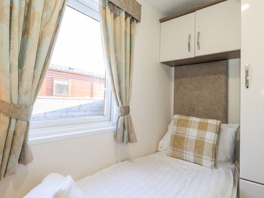 A small bedroom with a single bed pillows curtains and a window at Ursa Felmoor Park