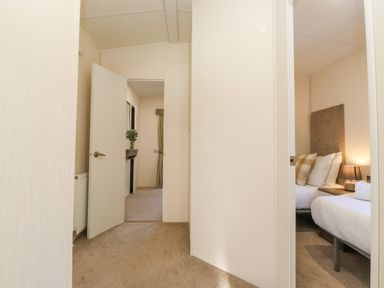 A hallway with doors leading to a bedroom and another room with a vaulted ceiling at Ursa Felmoor Park