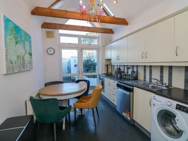 A kitchen with a round dining table and four chairs three have different colors and wall cabinets at 83 Upper John Street in Wexford Town County Wexford