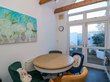 A dining area with a round wooden table and four colorful chairs next to glass doors leading to an outdoor patio at 83 Upper John Street in Wexford Town County Wexford