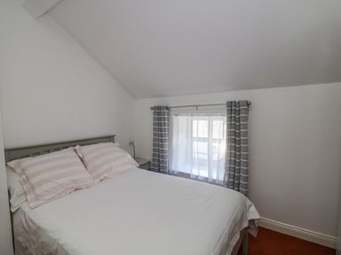 A bedroom with a bed a bedside table and a window with curtains at 83 Upper John Street in Wexford Town County Wexford
