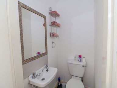 A small bathroom with a toilet and sink a mirror above the sink and glass shelves with folded towels at 83 Upper John Street in Wexford Town County Wexford