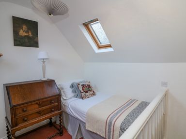 A small bedroom with a single bed a wooden desk with drawers a lamp a wall painting and a skylight window at 83 Upper John Street in Wexford Town County Wexford