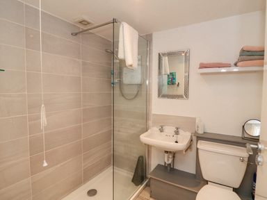 A bathroom with a shower area glass panel sink toilet and shelves with folded towels at 83 Upper John Street Wexford Town County Wexford