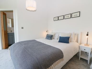 A bedroom with a bed and bedside tables with lamps at Pen-Y-Bryn in Llanfairpwllgwyngyll