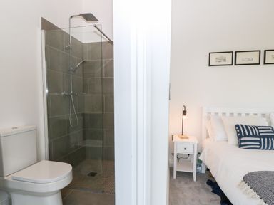 A bathroom with a toilet and glass shower next to a bedroom with a bed and nightstand at Pen-Y-Bryn in Llanfairpwllgwyngyll