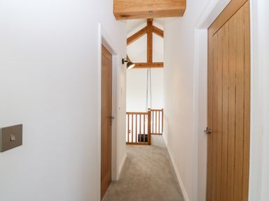 A hallway with wooden doors and wooden beams above at Pen-Y-Bryn in Llanfairpwllgwyngyll