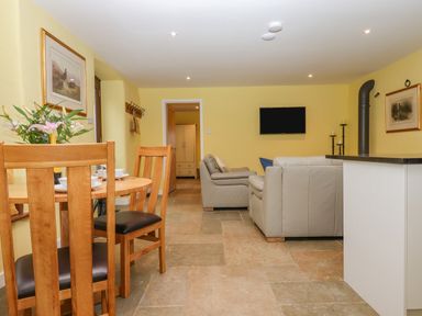 A living room with wooden dining table chairs and beige sofas at Bradley Stables in Withypool