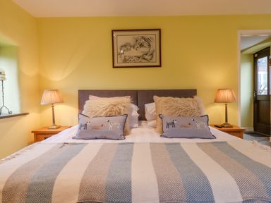 A bedroom with a bed with pillows and blanket and lamps on bedside tables at Bradley Stables in Withypool
