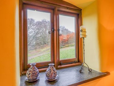 A window with two decorative candle holders and a tall candle stand on the windowsill at Bradley Stables in Withypool