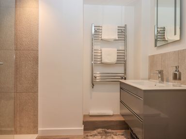 A bathroom with a towel rack holding two towels a sink with a cabinet and a mirror at Bradley Stables in Withypool