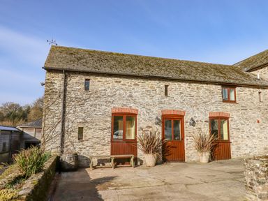 Stone building with three wooden framed doors and windows in a courtyard at Bradley Stables in Withypool