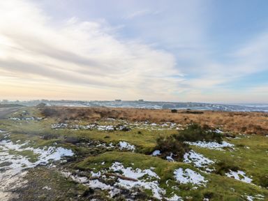 A rural landscape with patches of snow on grass and heathland under a partly cloudy sky at Bradley Stables in Withypool