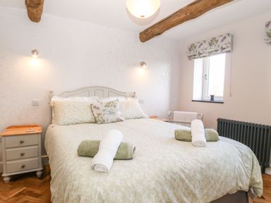 A bedroom with a bed and bedside tables with towels on the bed at Pips Barn in Brynteg near Benllech