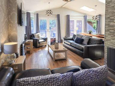 A living room with black leather sofas a wooden coffee table and armchairs at Ghyll Lodge Grasmere 25 White Cross Bay Windermere